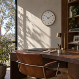 Brown wood frame silent wall clock above a home office desk