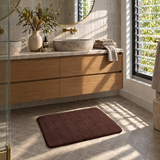 Brown plush bath mat in front of a double vanity ensuite