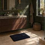 Dark blue plush bath mat in front of a timber vanity