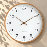 Silent wall clock with brown wood frame on a sunlit plaster wall
