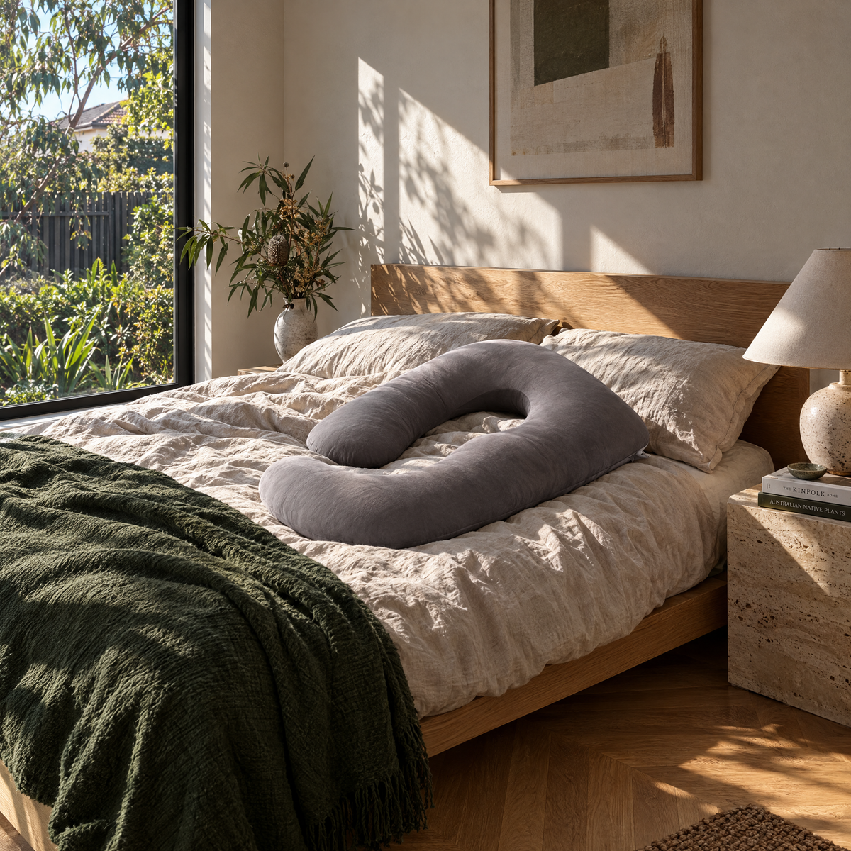 Grey U-shape pregnancy pillow on a main bedroom bed