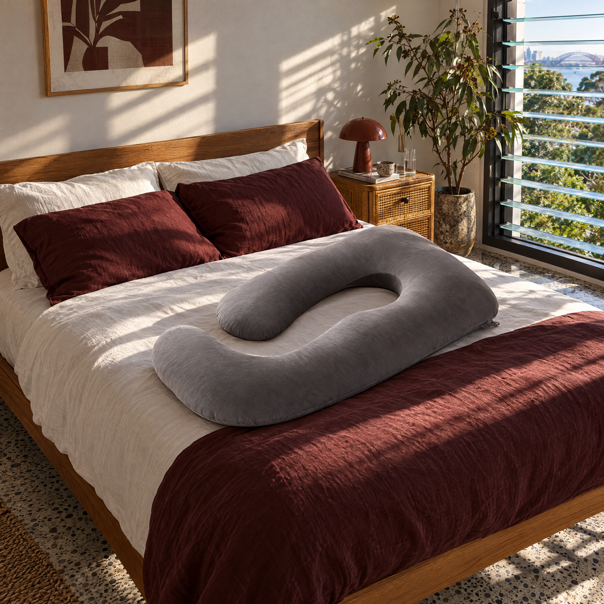 Grey U-shape pregnancy pillow on a guest bedroom bed