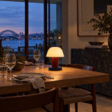 Red cordless mushroom lamp on a dining table at dusk