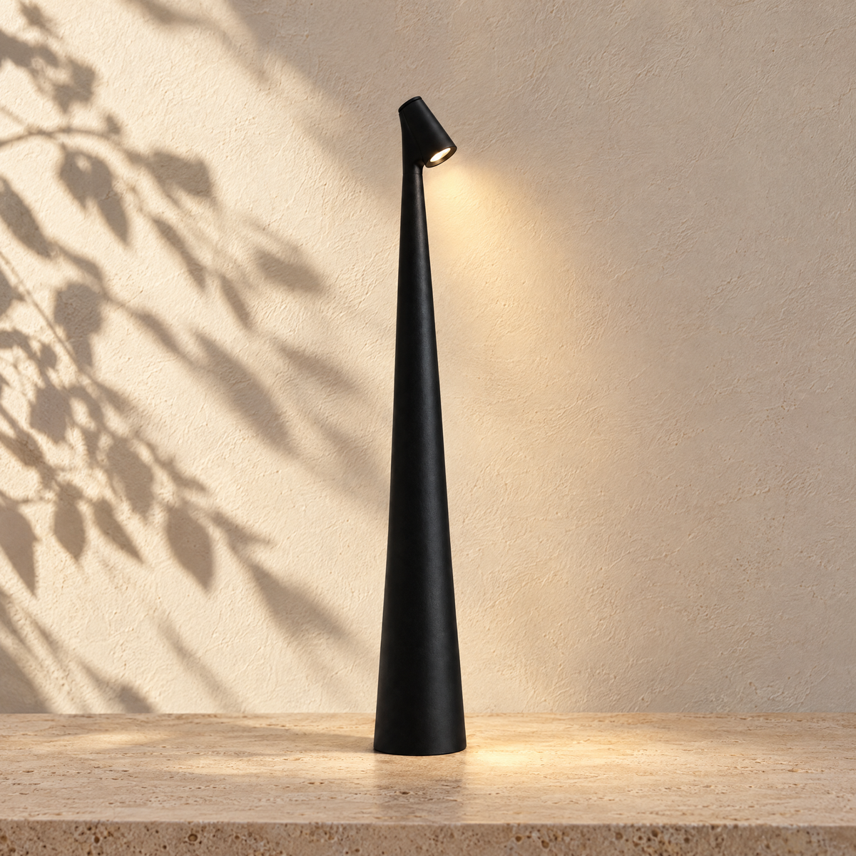 Black Aften cordless LED table lamp glowing against a sunlit plaster wall