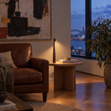 Brown cordless LED table lamp beside a leather armchair at dusk