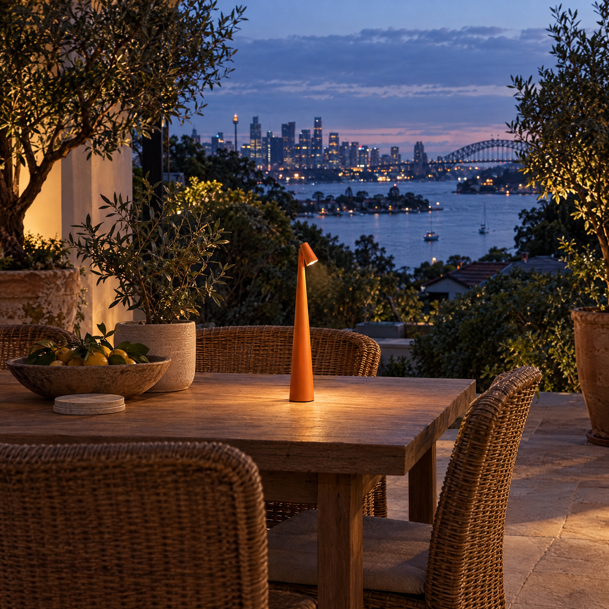 Orange cordless LED table lamp on an outdoor terrace table at dusk