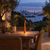 Orange cordless LED table lamp on an outdoor terrace table at dusk