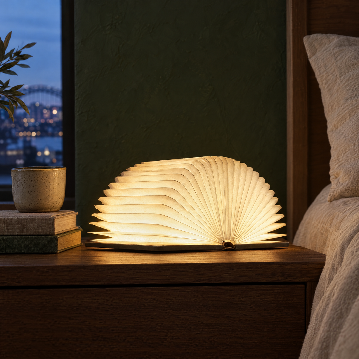 Lumibook foldable book lamp with wood covers glowing on a bedside table