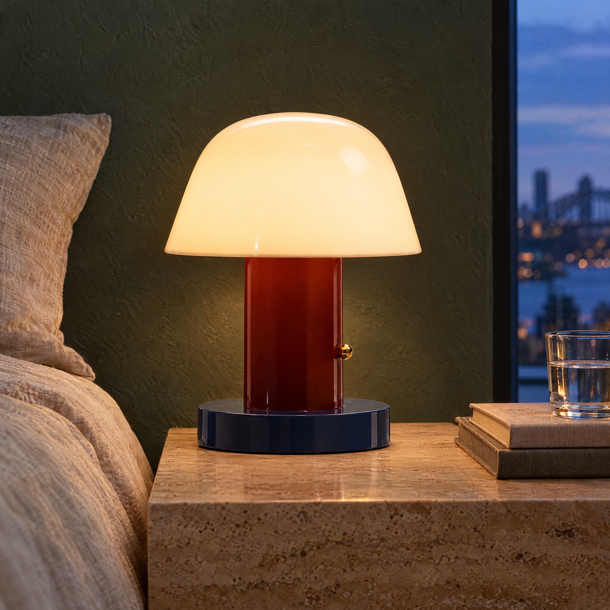 Red rechargeable mushroom lamp glowing on a travertine bedside table at dusk
