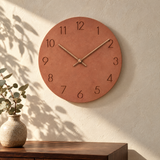 Nork minimalist wall clock in orange on a sunlit plaster wall