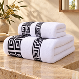 White terry towel set with Greek key border on a travertine vanity